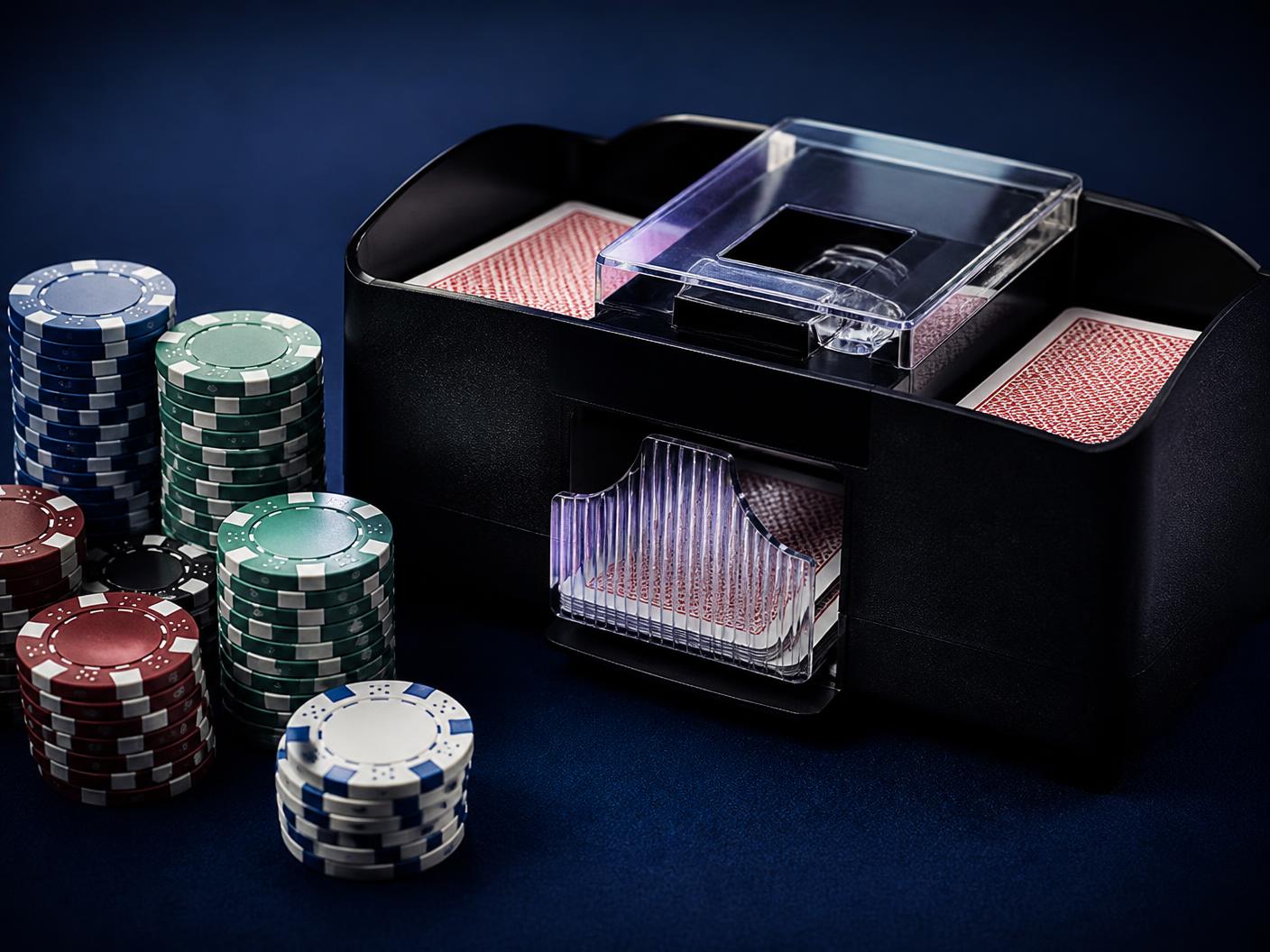Automatic card shuffler and stacks of casino chips on green felt